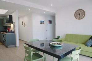 A modern kitchen with a dining area, a green sofa, and a wall clock. - Aetnamare: A 360° View (Mascalucia)
