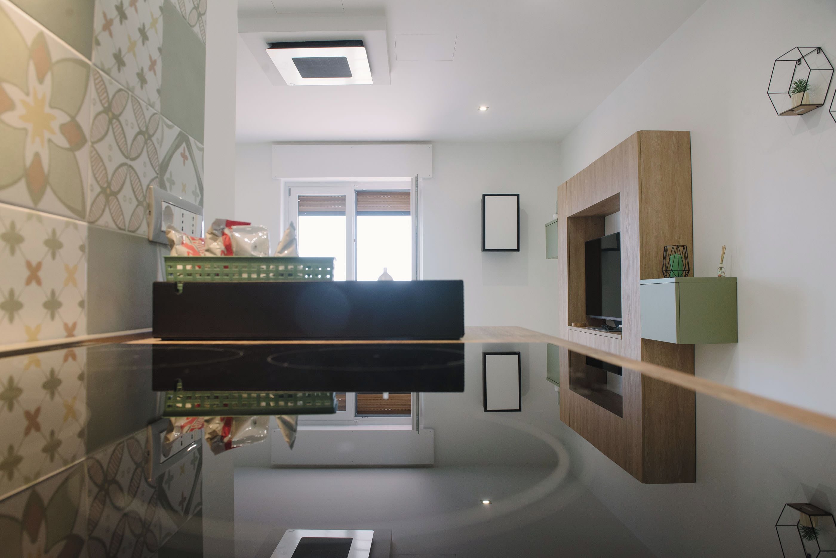 A modern kitchen with a central island, a built-in oven, and a window with blinds.