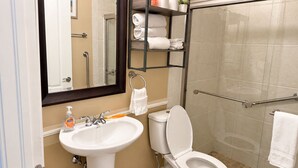 A bathroom with a white sink, toilet, and shower area. - The Canal Cottage (Fort Myers)
