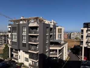 Un edificio residencial de varios pisos con balcones, una grúa de construcción y vistas despejadas del entorno.