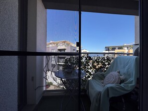 Un balcón con una silla, una mesita y vistas a edificios.