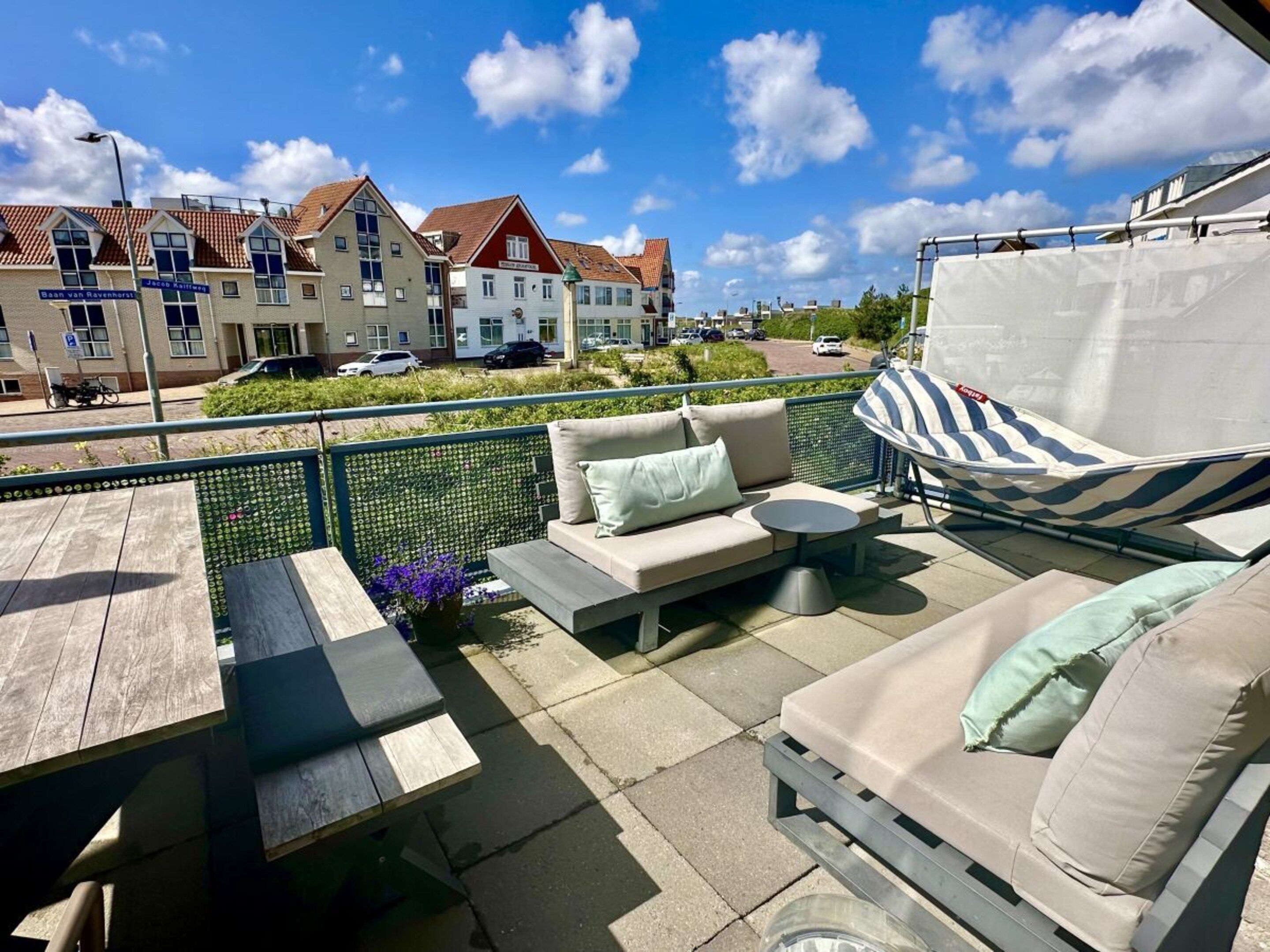 Eine Terrasse im Freien mit einer Couch, einem Tisch und einer Hängematte.