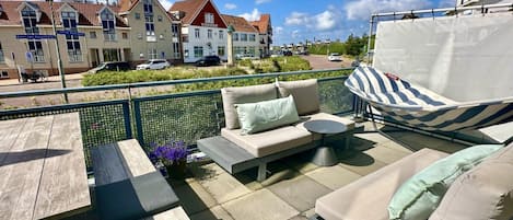 Une terrasse extérieure avec un canapé, une table et un hamac.