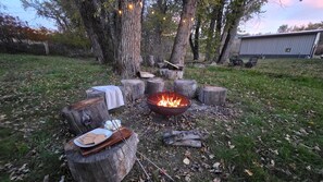 A campfire setup with logs, a fire pit, and a plate with food. - COMING SOON! Enjoy Montana all year round, 5 bedrooms for your get away!  (Gallatin Gateway)