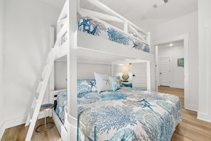 A bunk bed with a nautical-themed bedspread, a small table with a lamp, and a door leading to another room. - Dama Oasis - Luxurious Home W/ Private Pool! (Panama City Beach)
