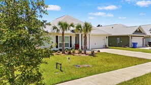 A residential property with a garage, a covered porch, and a well-maintained lawn. - Dama Oasis - Luxurious Home W/ Private Pool! (Panama City Beach)