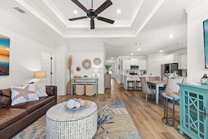 A spacious living room with a brown leather sofa, a round coffee table, and a ceiling fan. - Dama Oasis - Luxurious Home W/ Private Pool! (Panama City Beach)