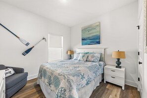 Une chambre à coucher avec un lit, des tables de chevet, un tableau et une lampe fixée au mur.