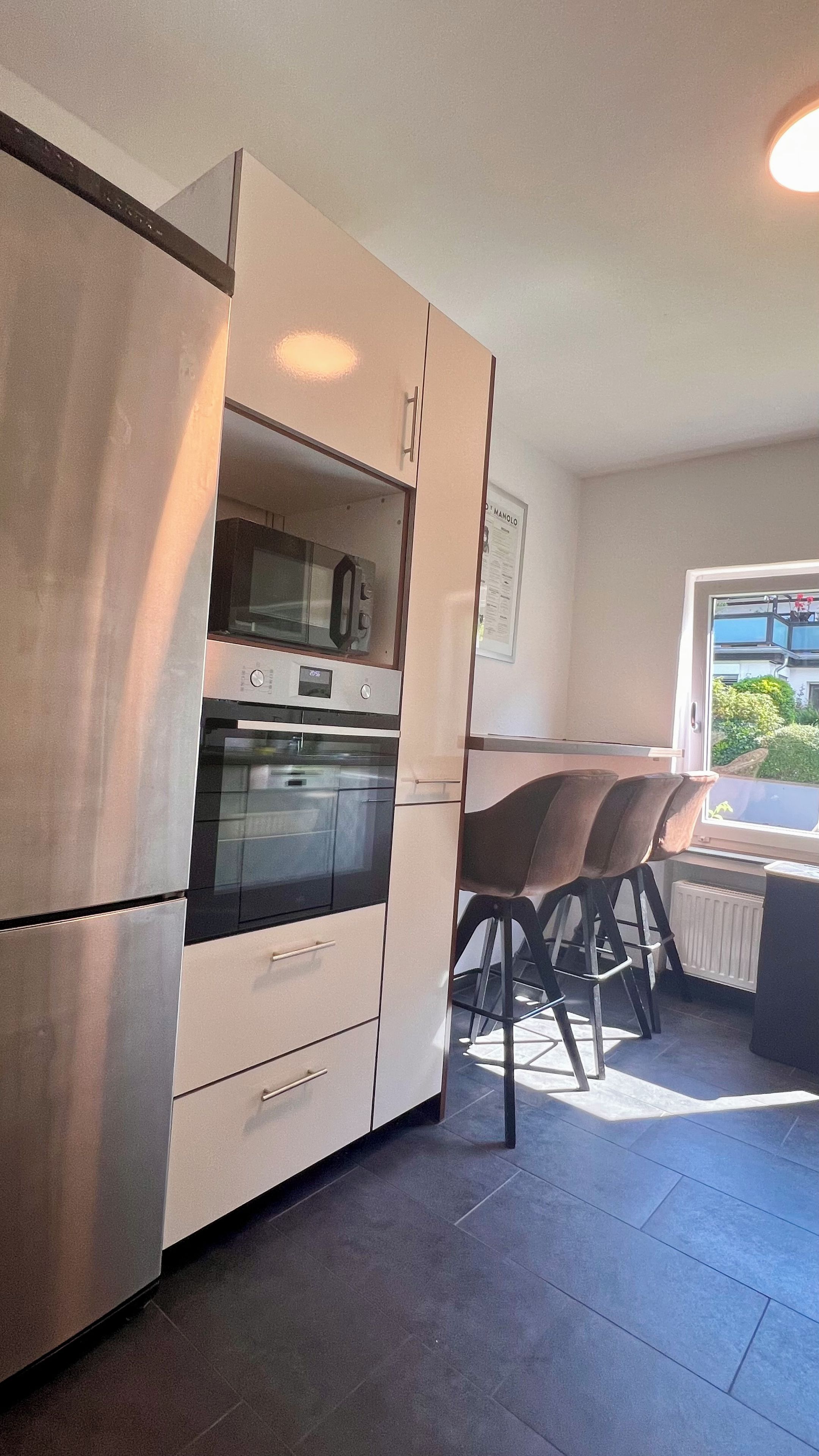 Eine Küche mit Einbauofen, Kühlschrank und einer Essecke mit Tisch und Stühlen.