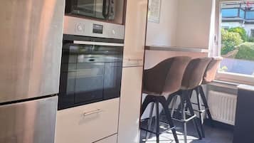 Eine Küche mit Einbauofen, Kühlschrank und einer Essecke mit Tisch und Stühlen.
