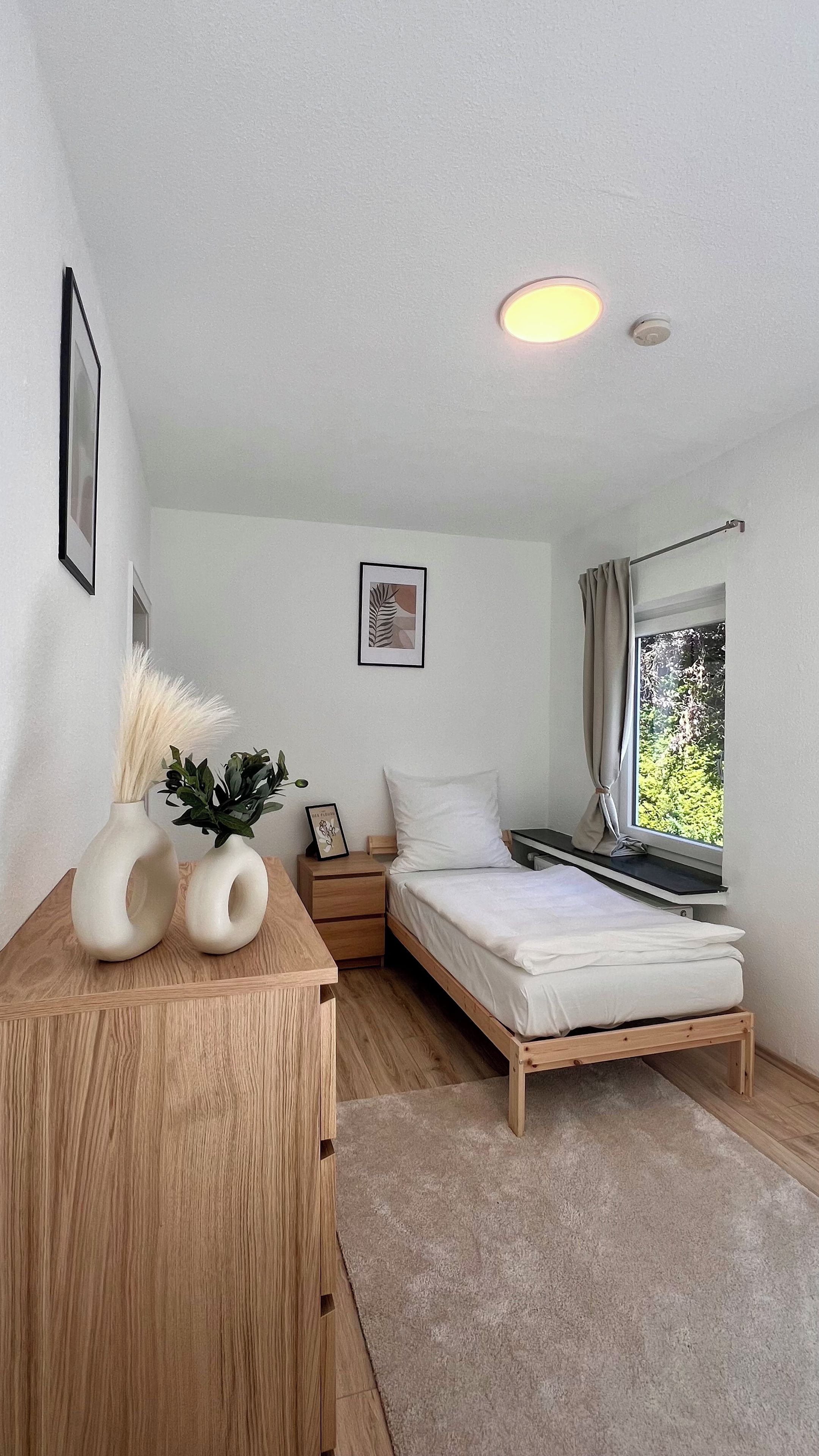 Ein Schlafzimmer mit einem Bett, einem Nachttisch und einem Fenster mit Vorhängen.