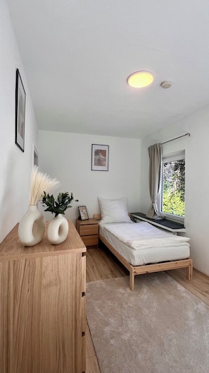 A bedroom with a bed, bedside table, and a window with curtains.
