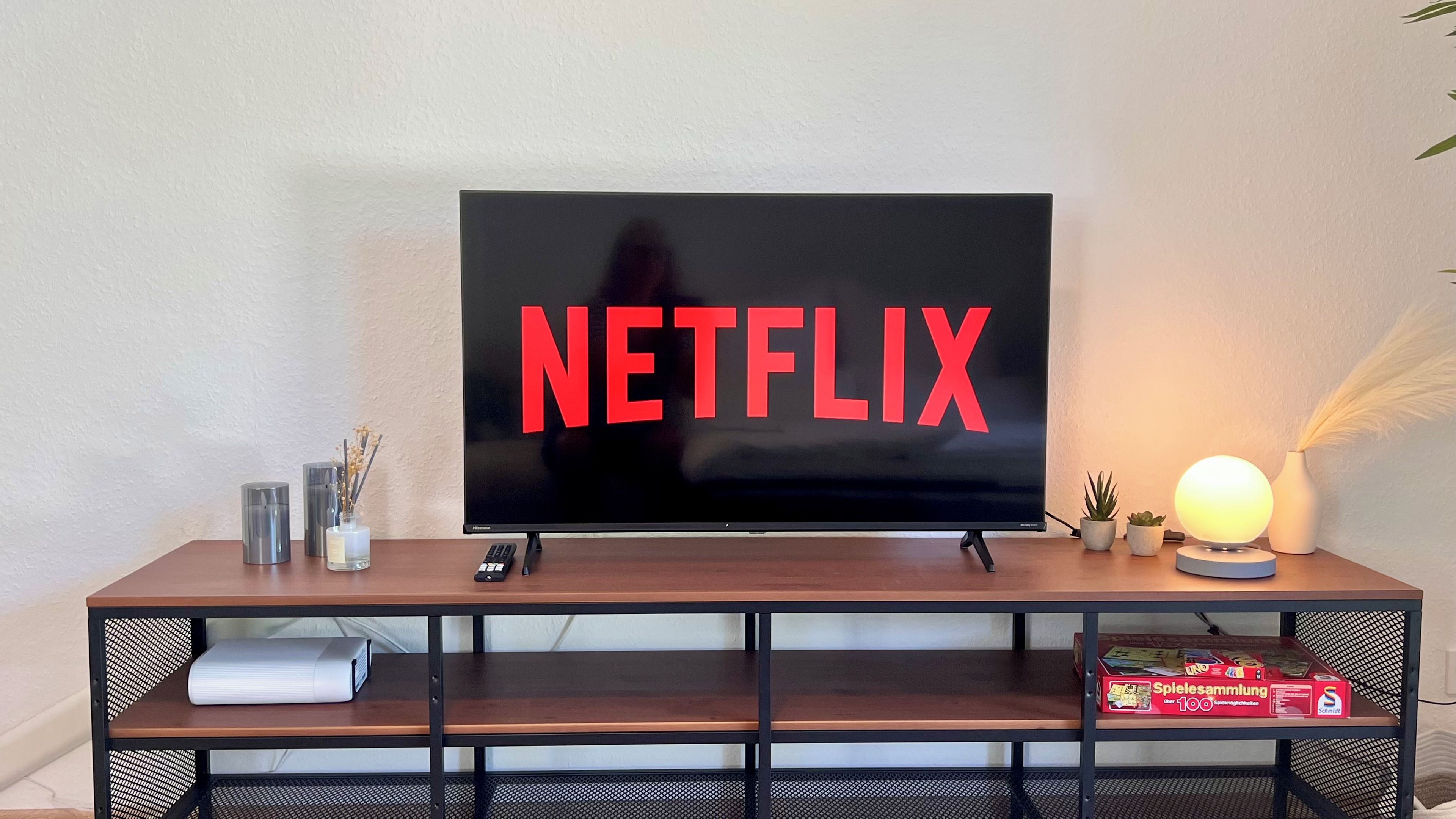 Ein Fernseher mit dem Netflix-Logo auf einem Holzständer mit Ablagefläche darunter.