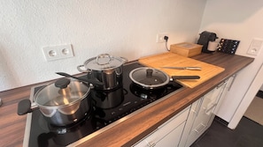 Eine Küche mit einem Herd, Töpfen, einem Schneidebrett und einer Kaffeemaschine.