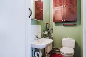 Un baño con lavamanos blanco, inodoro y armarios de madera.