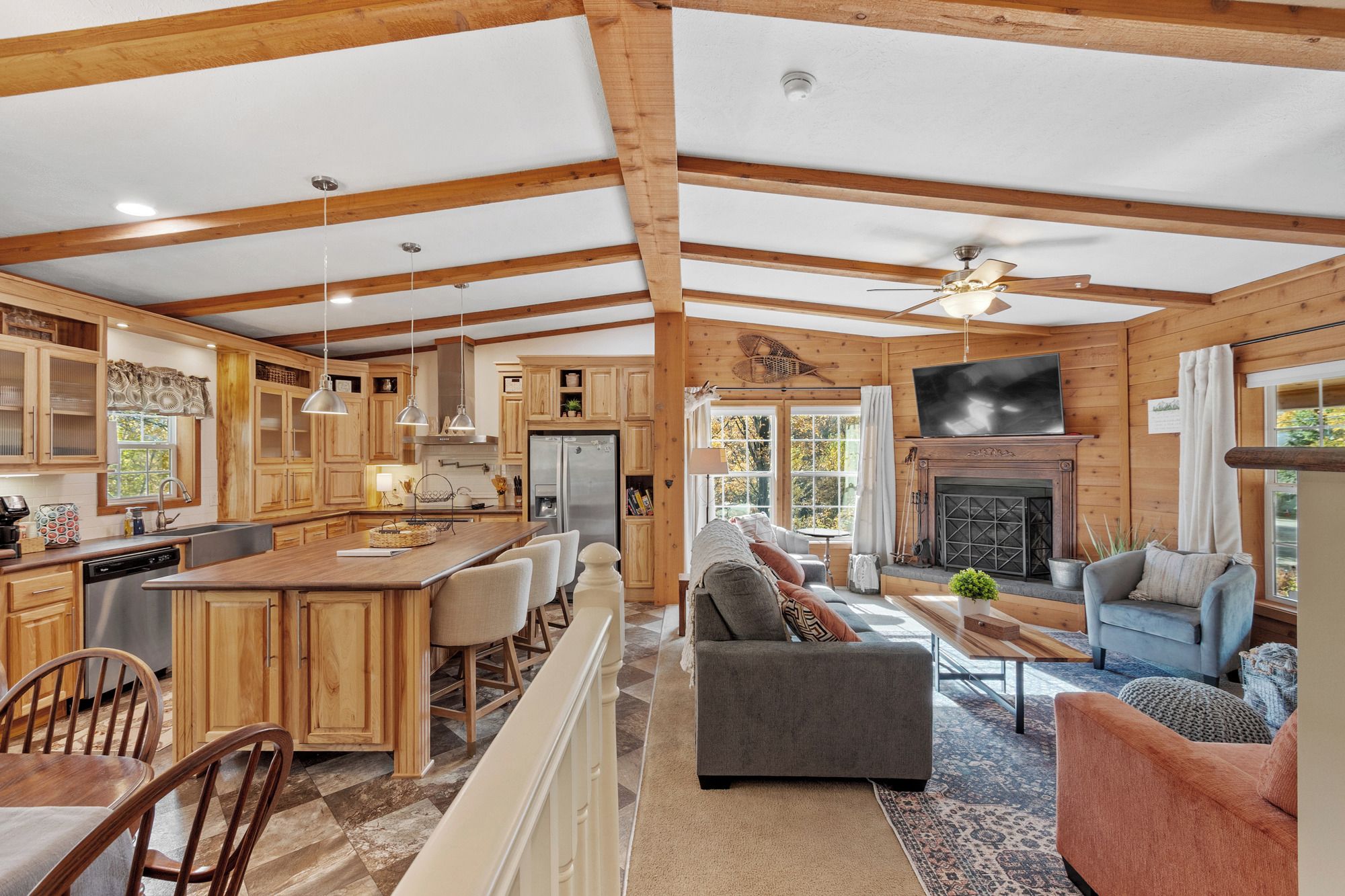 Amplia sala de estar con chimenea, comedor con una isla grande y cocina con armarios de madera.