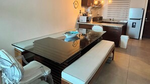 A modern kitchen with a central island, a dining table with chairs, and a refrigerator. - Private apartment | Pool and beach views | Sleeps 7 | Fully equipped | Wi-Fi and balcony (Mahahual)