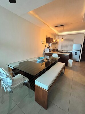 Una cocina moderna con una isla central, una mesa de comedor con sillas y un refrigerador.