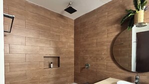 A modern bathroom with a freestanding bathtub, a round mirror, and a wooden wall design. - Private apartment | Pool and beach views | Sleeps 7 | Fully equipped | Wi-Fi and balcony (Mahahual)