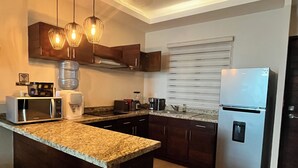 A modern kitchen with a central island, stainless steel appliances, and pendant lighting. - Private apartment | Pool and beach views | Sleeps 7 | Fully equipped | Wi-Fi and balcony (Mahahual)