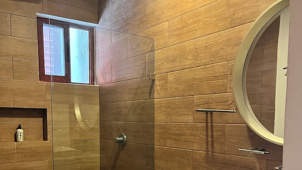 A modern bathroom with a glass-enclosed shower, a toilet, a sink with a mirror, and neatly rolled towels. - Private apartment | Pool and beach views | Sleeps 7 | Fully equipped | Wi-Fi and balcony (Mahahual)