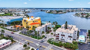A coastal cityscape with a prominent yellow building, a marina, and a road with vehicles. - The Baycrest | Heated Pool, Beach and Bay Access (Treasure Island)