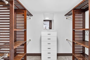A walk-in closet with wooden shelving on either side and a white storage unit in the center. - The Baycrest | Heated Pool, Beach and Bay Access (Treasure Island)