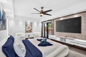 Een moderne slaapkamer met een groot bed, een plafondventilator, een televisie en uitzicht door de glazen deur.