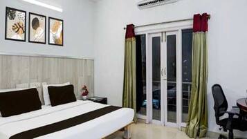 A hotel room with a bed, a desk, and a sliding glass door.