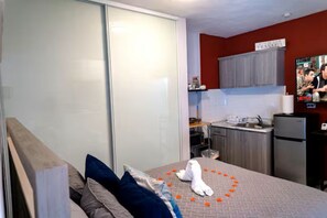 A bedroom with a bed, pillows, a white robe, and a heart-shaped arrangement of orange flowers on the bed. - Cozy Aguada, PR Studio, Relax, Unwind & Enjoy (Aguada)