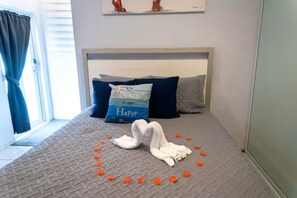 A bed with a swan-shaped pillow arrangement and a pillow with text. - Cozy Aguada, PR Studio, Relax, Unwind & Enjoy (Aguada)