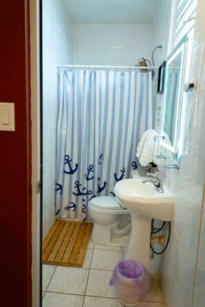 A small bathroom with a white sink, a toilet, and a shower curtain with anchor patterns. - Cozy Aguada, PR Studio, Relax, Unwind & Enjoy (Aguada)