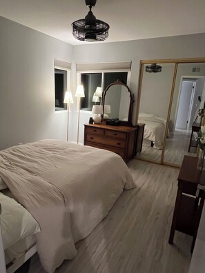 A bedroom with a large bed, a dresser, a mirror, and a ceiling fan. - Spacious 3-bedroom house in Vista perfect for your getaway (Vista)