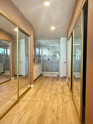 A hallway with a wooden floor, a glass shower enclosure, and a door leading to a bathroom. - Spacious 3-bedroom house in Vista perfect for your getaway (Vista)