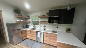 A modern kitchen with wooden cabinets, a stainless steel refrigerator, and a built-in oven. - Soothing 1-bedroom house with AC in charming Spanish Fork (Spanish Fork)