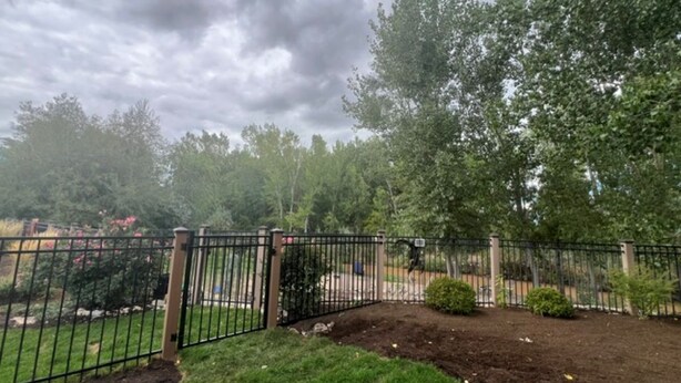 A fenced garden area with a gate, surrounded by trees and shrubs. - Soothing 1-bedroom house with AC in charming Spanish Fork (Spanish Fork)