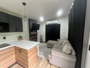 Um espaço de estar moderno com cozinha, televisão de tela plana, sofá e área de jantar.