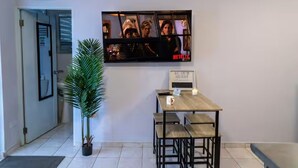 Un passadís amb una taula de recepció, un senyal que indica la casa de platja i una pantalla de televisió que mostra una escena amb el logotip de Netflix.