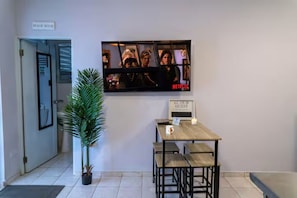 Un pasillo con una recepción, un cartel que indica la casa de playa y una pantalla de televisión mostrando una escena con el logo de Netflix.