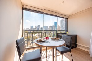 Ein Balkon mit einem Tisch für zwei Personen, mit Blick auf eine Stadtlandschaft.