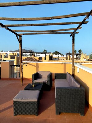 Eine Dachterrasse mit Korbmöbeln und einer Pergola.