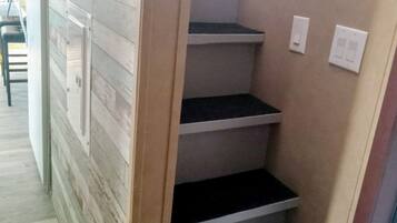 Una escalera con barandilla de madera y pared color crema.