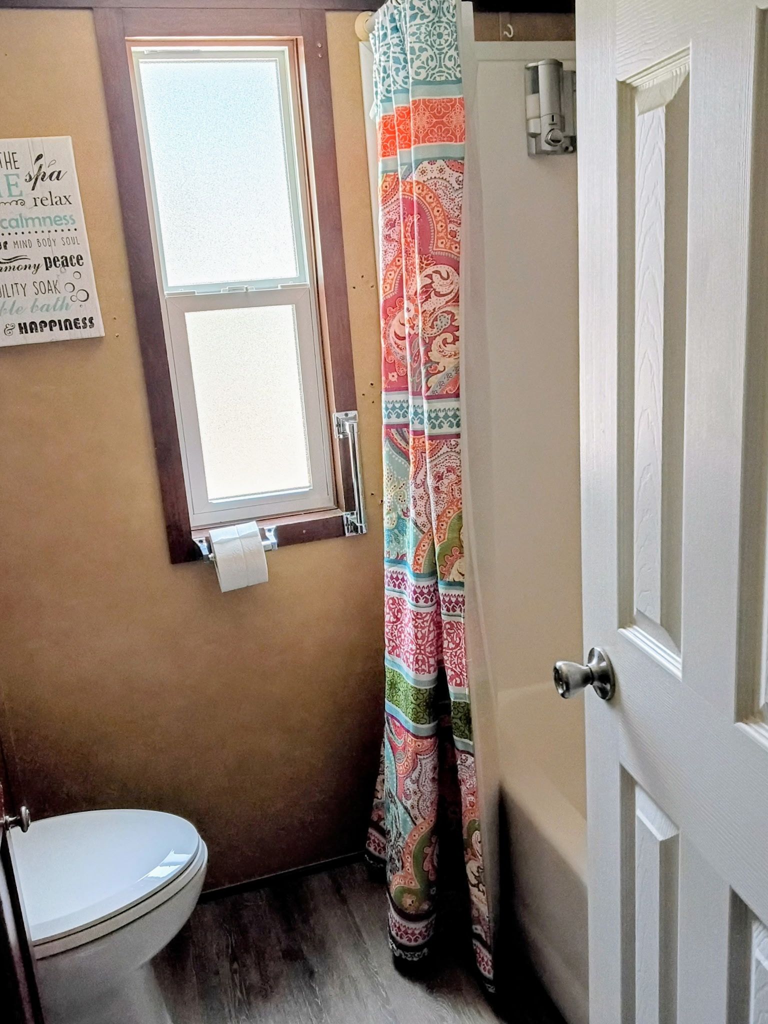 A bathroom with a toilet, a window, and a door.