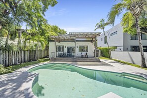 Una casa moderna con piscina, terraza de madera y pérgola.