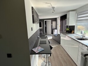 Una cocina moderna con comedor, refrigerador y ventana con cortinas.