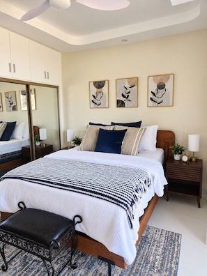 A bedroom with a bed, bedside tables, a bench, and artwork on the wall. - Chic 1BR Island Retreat |  Paradisiac, Jamaica (Llandovery)