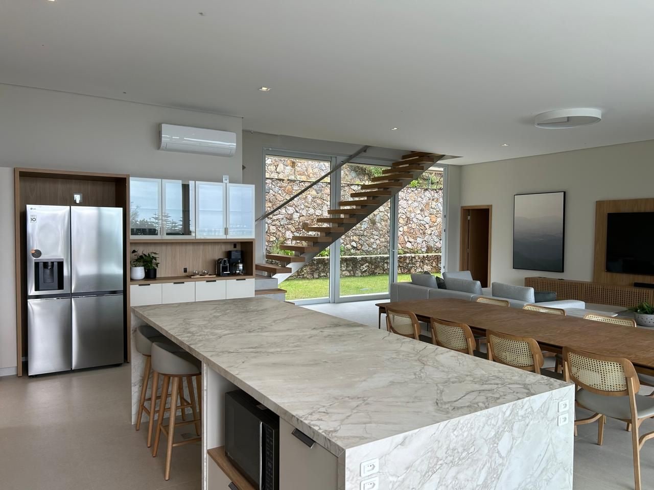 Una cocina moderna con encimera de mármol, electrodomésticos integrados y una zona de comedor con mesa y sillas de madera.