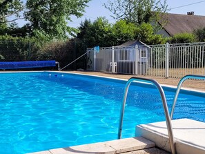 A clear blue swimming pool with a metal ladder and a fenced area. - Authentic Gite With Terrace and Shared Pool (Saint-Saud-Lacoussiere)