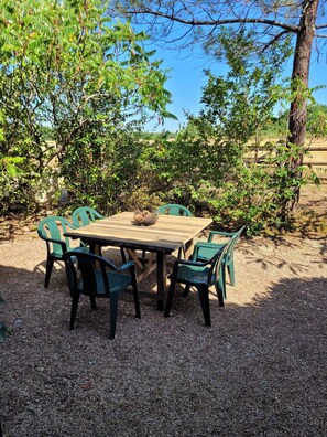 Una mesa de madera con sillas en un jardín.