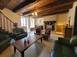 Una sala de estar amplia con chimenea, sofás de cuero, una mesa de centro de madera y una escalera.